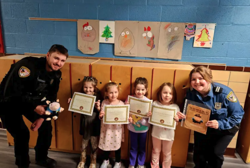 children pose with police officers and stuffed pig, Kris P. Bacon, as a part of HPD outreach