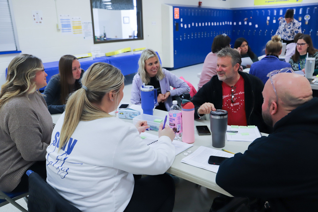 staff are sitting at a table with workbooks and drinks on the table