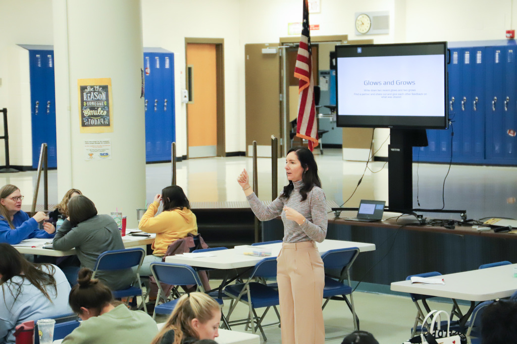 a woman presents in front of a room of teachers