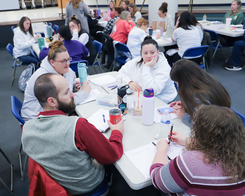People are sitting at a table with work books