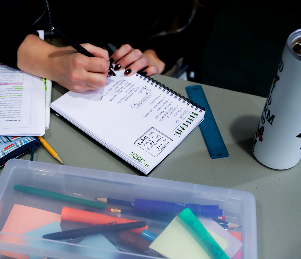 a womans hand is writing notes in a notebook