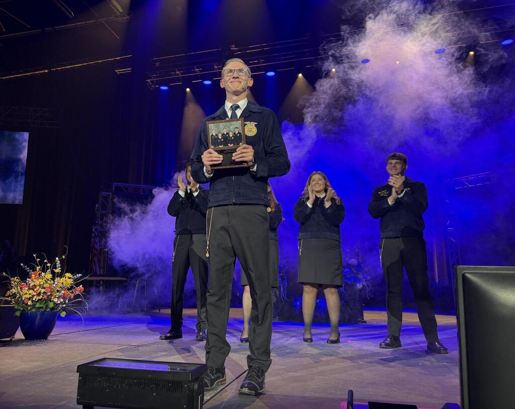 Owen Torrance standing on a stage with a plaque.