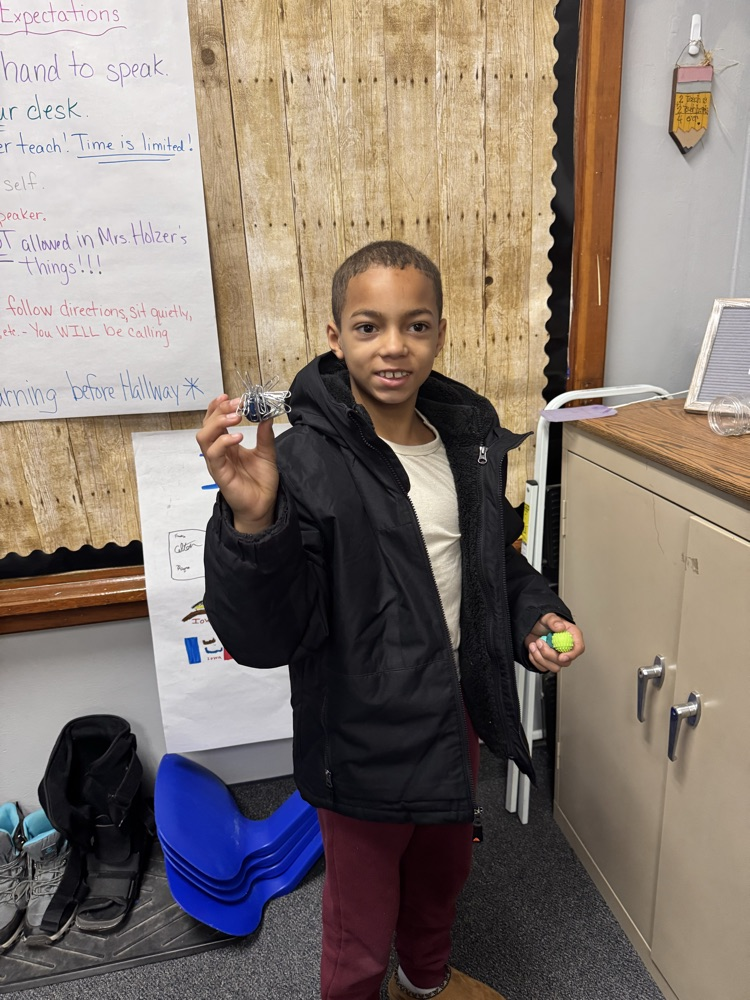a boy using a magnet and lots of paperclips