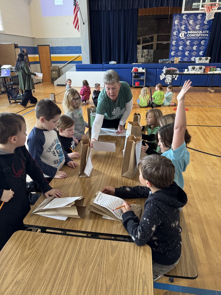 students at table listening to a teacher