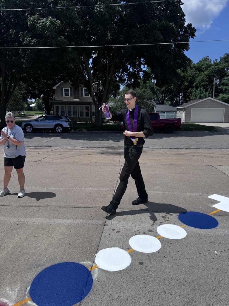 Priest blessings a painted rosary on the sidewalk