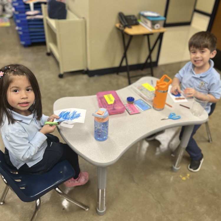 2 pre-k 4 students sitting at their desks cutting a Jonah and the Whale craft 