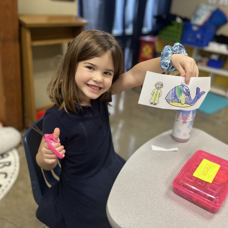 a pre-k 4 student smiling and showing their Jonah and the whale coloring sheet