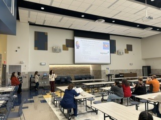 Families attend Senior Parent Information Night as a school counselor presents college and career planning resources.
