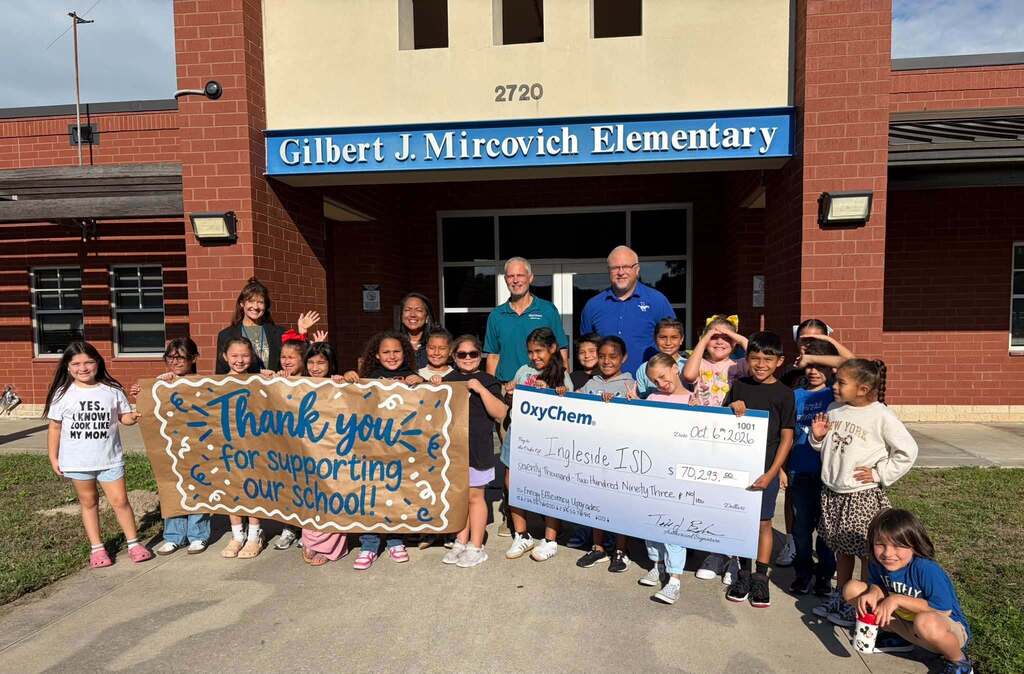 Children pose with a check and banner reading "Thank you for supporting our school!" outside an elementary school.