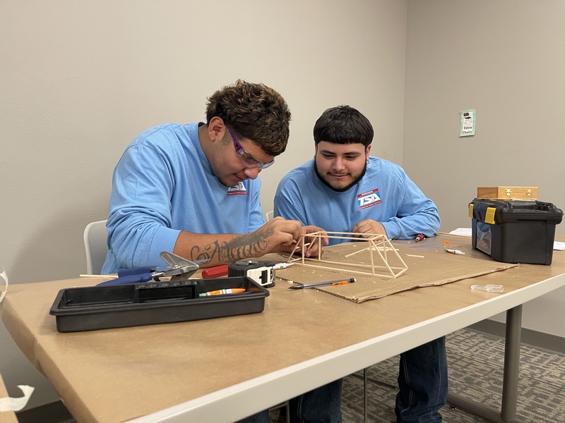 Two students construct a bridge