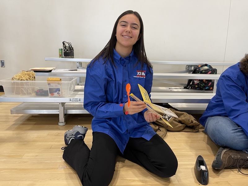 student smiles and holds plane