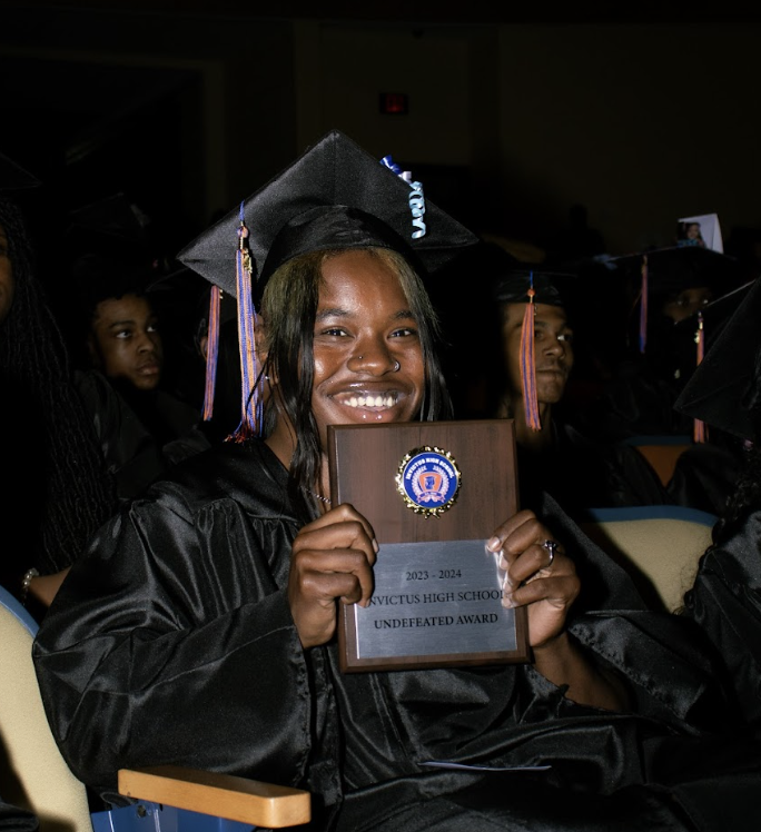 A graduate holds her plaque for the undefeated award
