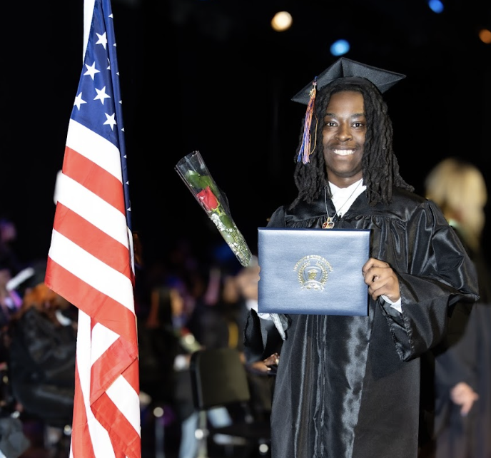 A graduate shows off his diploma on stage at graduation