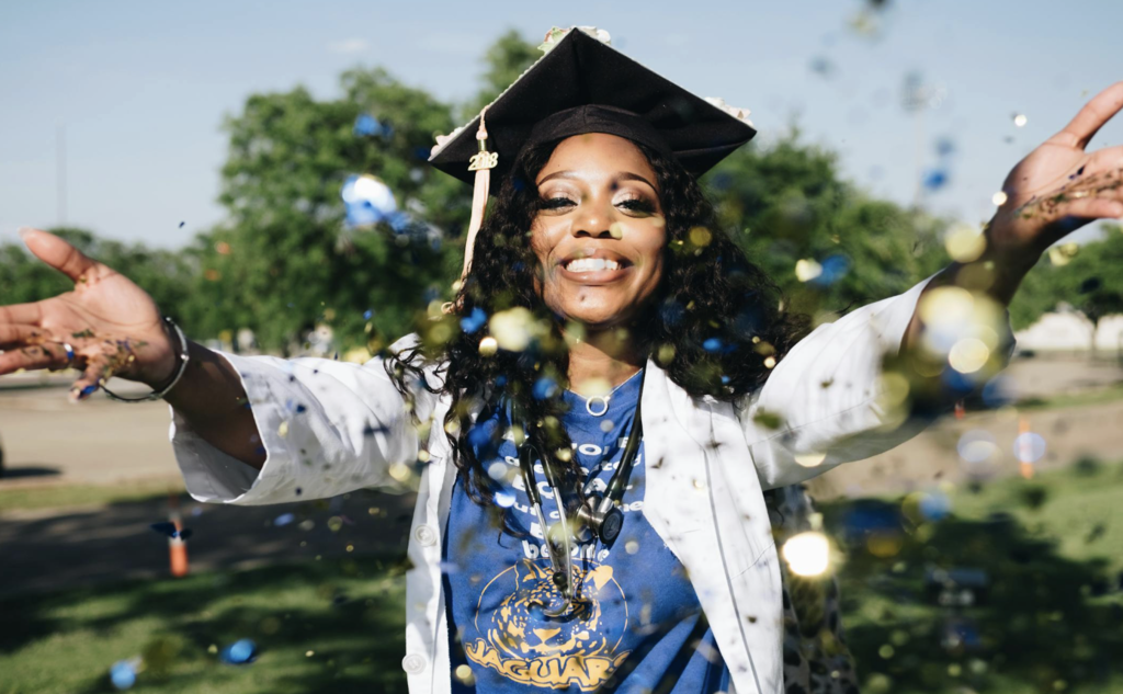A graduate smiles and throws confetti