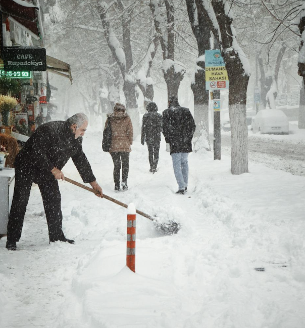 Man shoveling snow on a snowy populated street