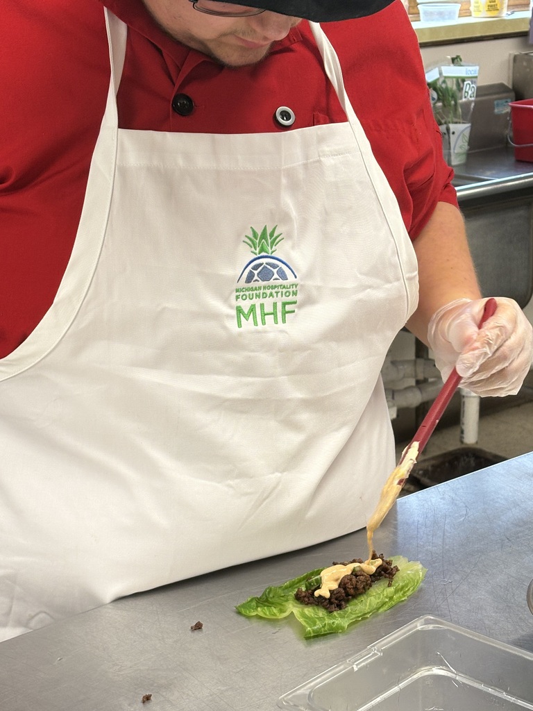 student putting sauce on something brown on a leaf of lettuce