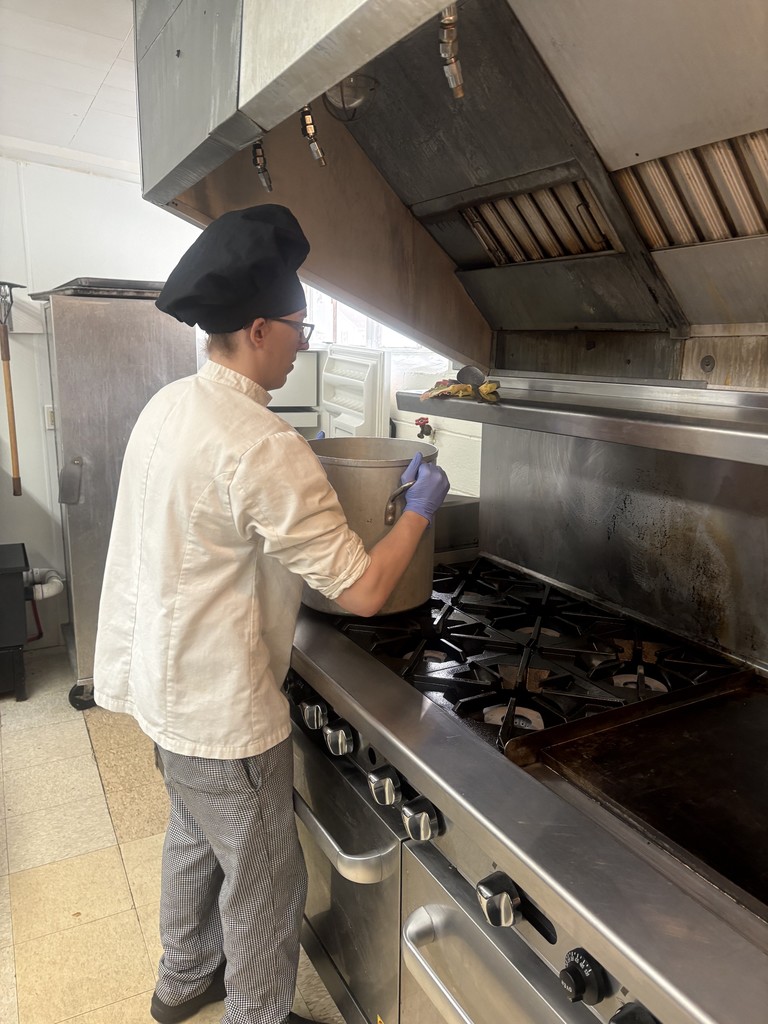 student chef lifting large pot