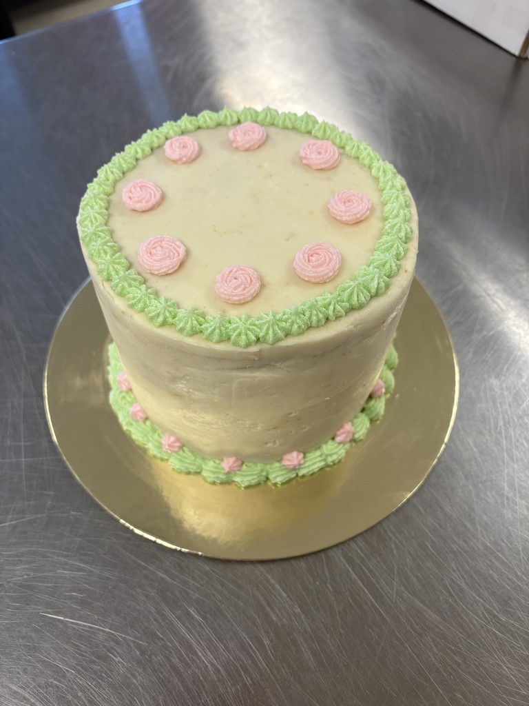 Cream colored cake with green and pink accents
