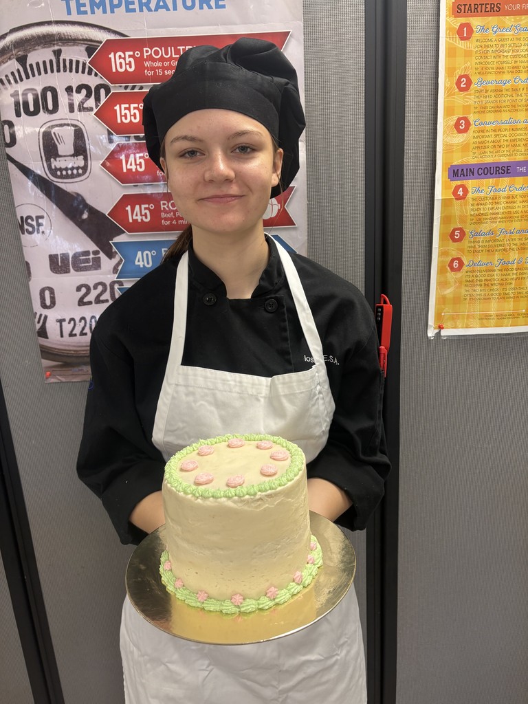 student holding cake decorated with green and pink accents