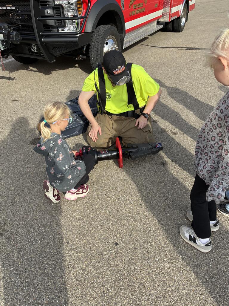 Fire fighter demonstrating an extracation tool with a student.