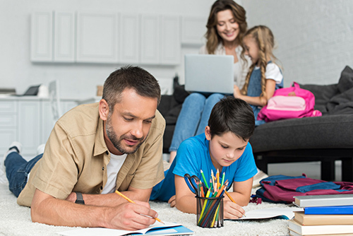 father helping son with homework in front of mother helping daughter