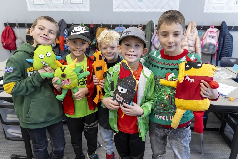 students hold stuffed monsters
