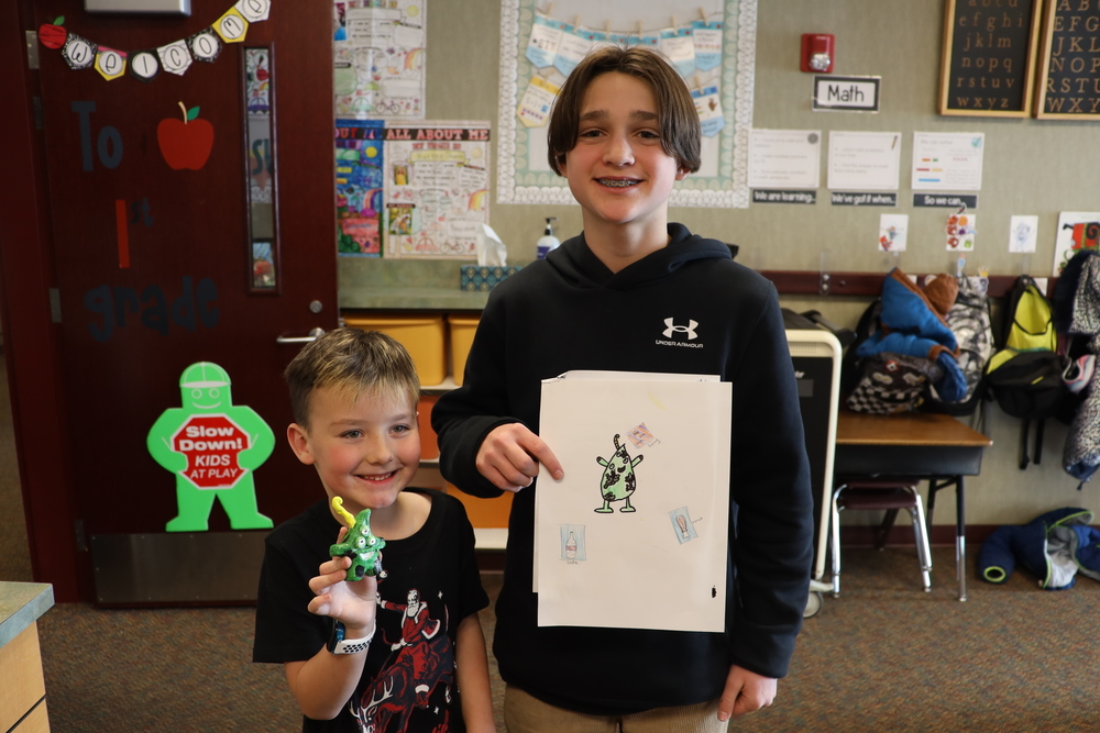 An elementary student and middle school student show the collaborative project they created.