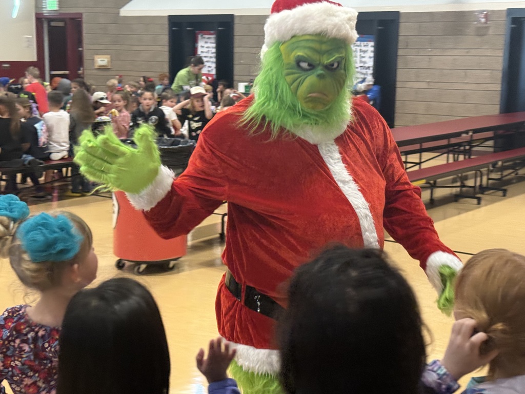An individual dressed as The Grinch gives students high 5s.