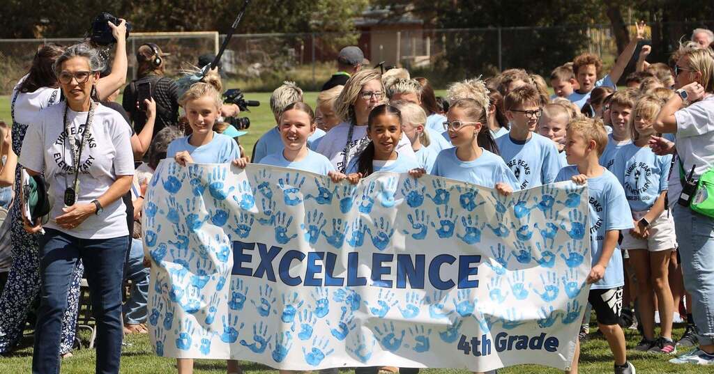 Students carry the value banner "Excellence"