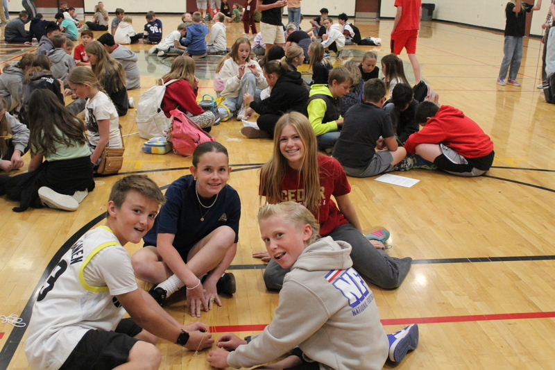 students sitting on gym floor