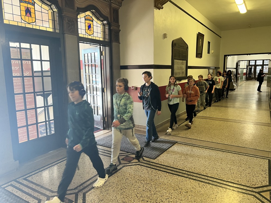 Students walk along a hallway wearing a listening device