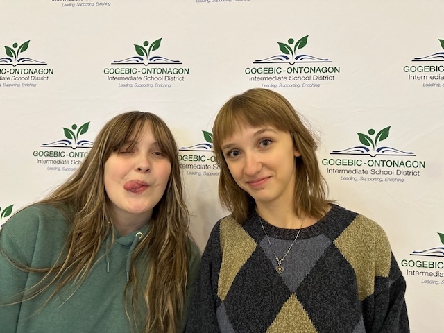 One student sticks her tongue out at the camera while the other one smiles