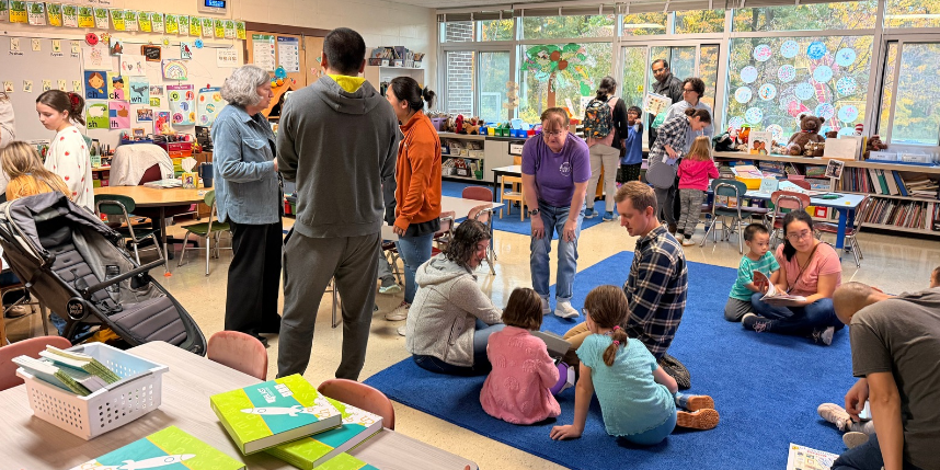 A classroom filled with young children, parents, and teachers engaging in different activities