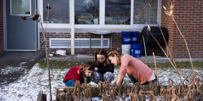 Two Enfield Elementary students crouched down outside with Farmer Melissa as they read the temperature.