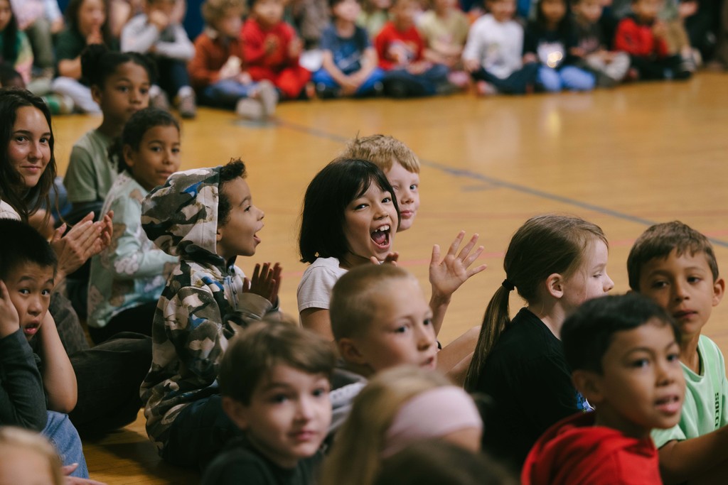 Students sitting on the gym floor smiling 