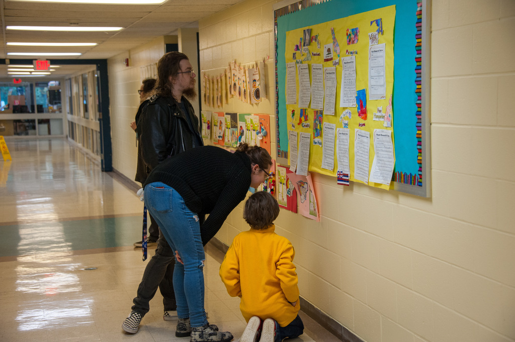 a student and their parent looking at student work on a hallway wall