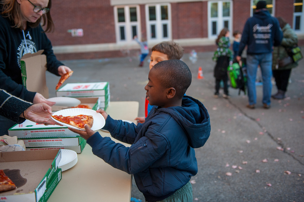 Student in line to get pizza being handed a plate