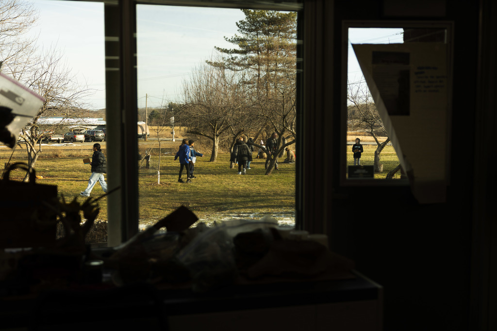 Students seen through a classroom window out in the orchard at Enfield Elementary as part of their weather project unit. 