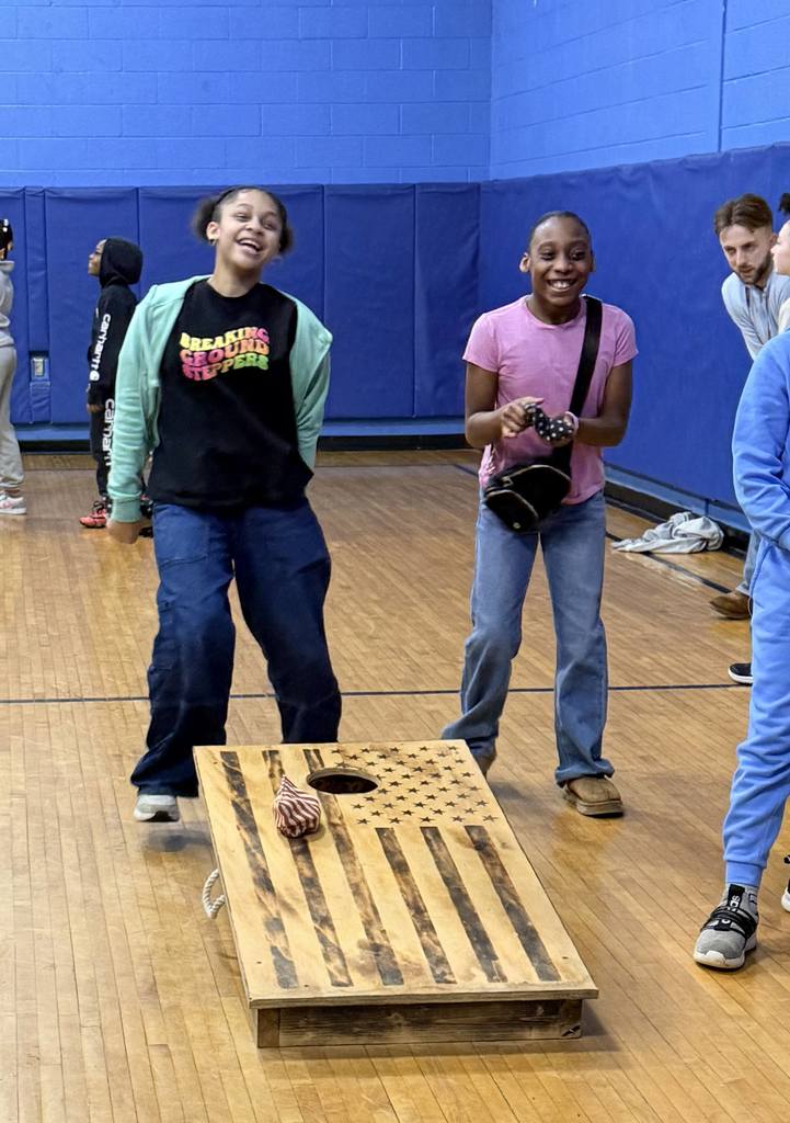 Two bjm students in the gym playing cornhole