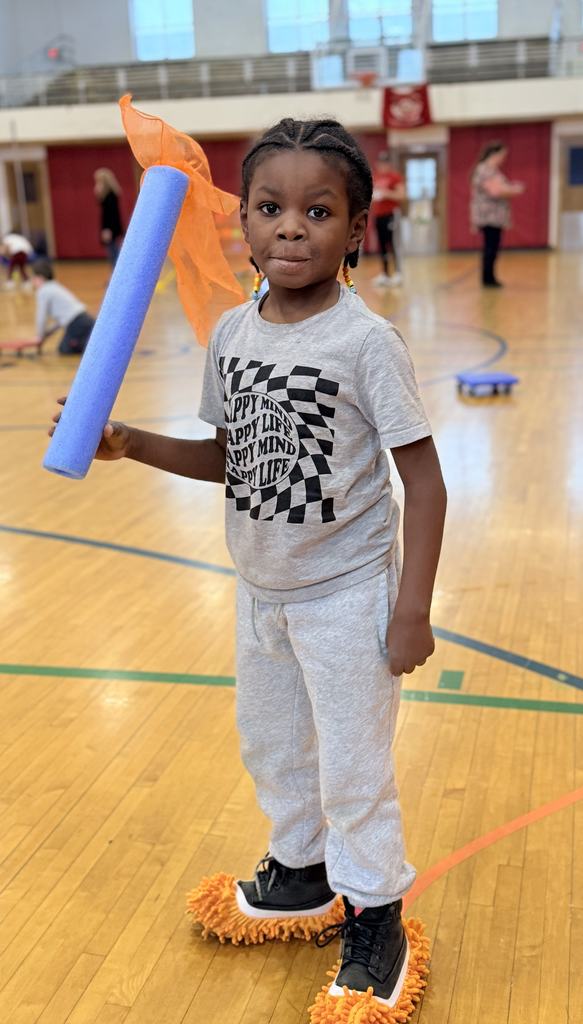 BJM student in the gym holding up a noodle with a scarf on top posing for a photo. 