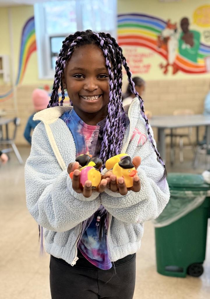BJM student in the cafeteria holding up rubber ducks posing for a photo.