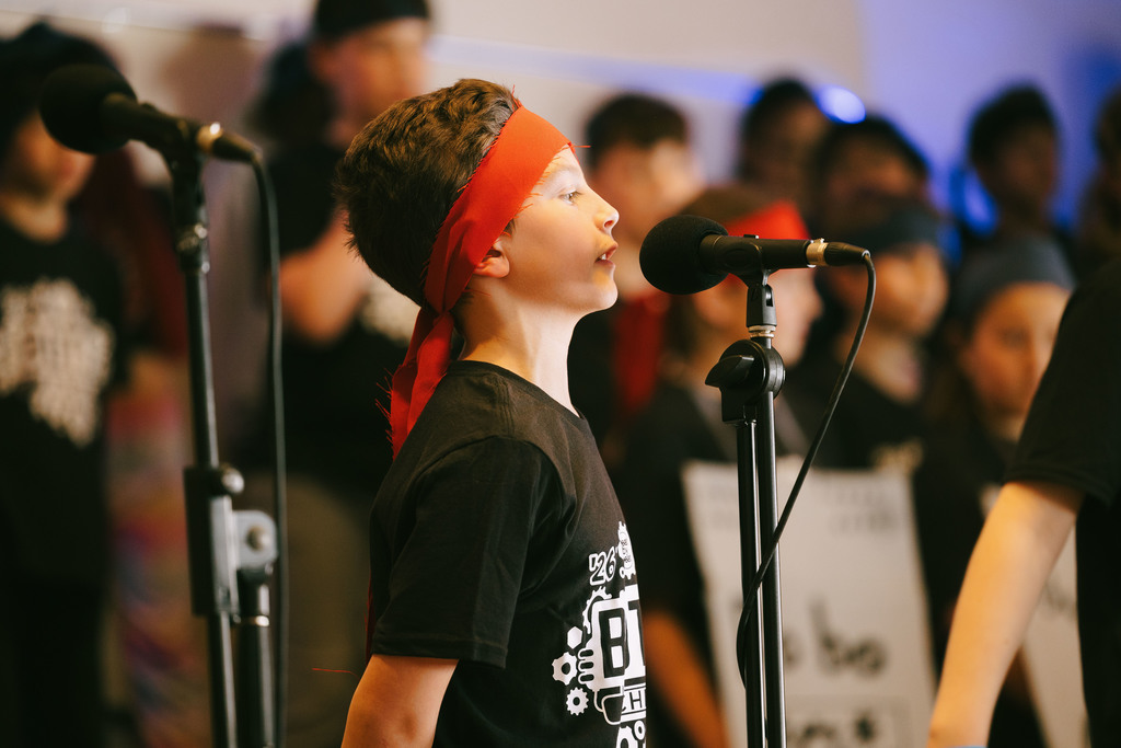 5th grade student singing on stage in the production of BOTS!