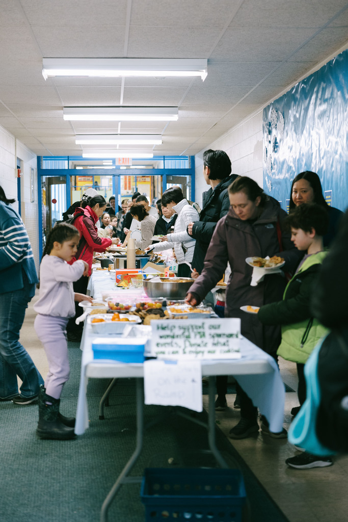 Families on either side of a long table, getting food.