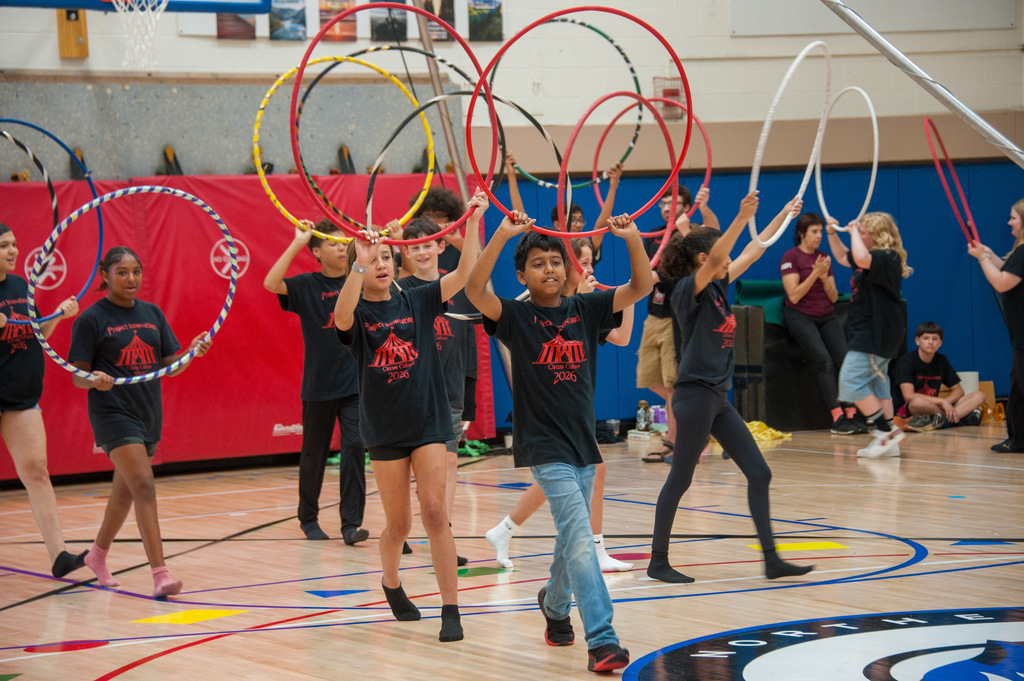A group of young people on a basketball court, performing a coordinated hula hoop routine.