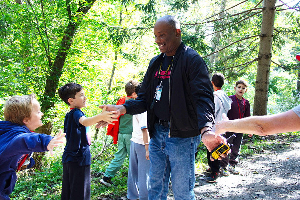 A group of students high five Mr. Brown at the finish line of the fun run