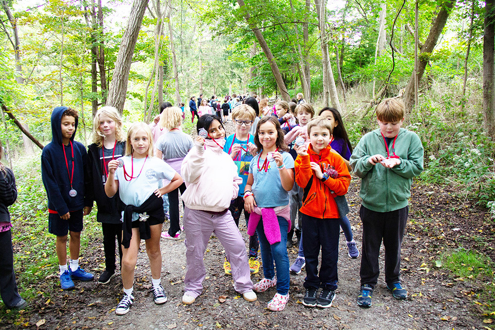 A group of children standing on the trail together holding up their fun run medals