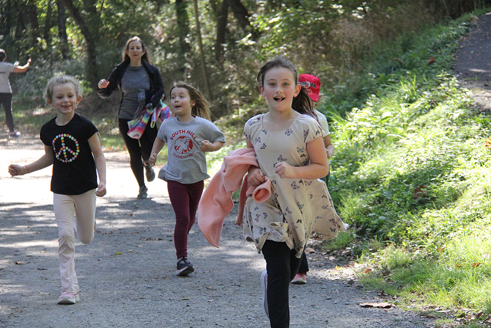 Three children run on the rec trail