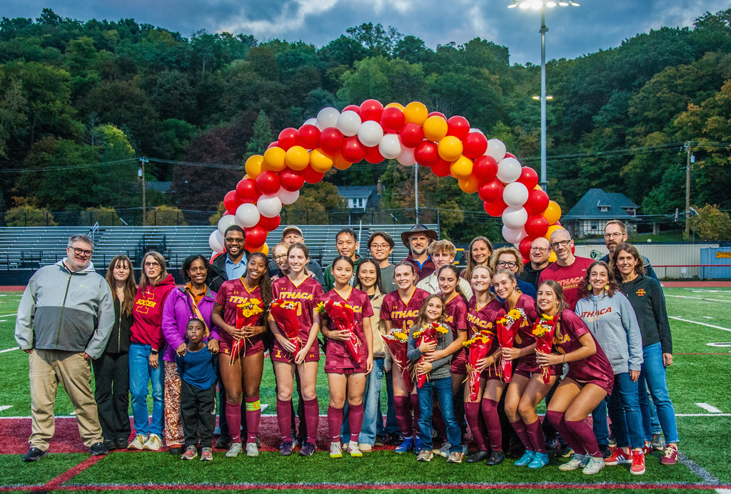 The seniors and their families pose on senior night in front of a balloon arch
