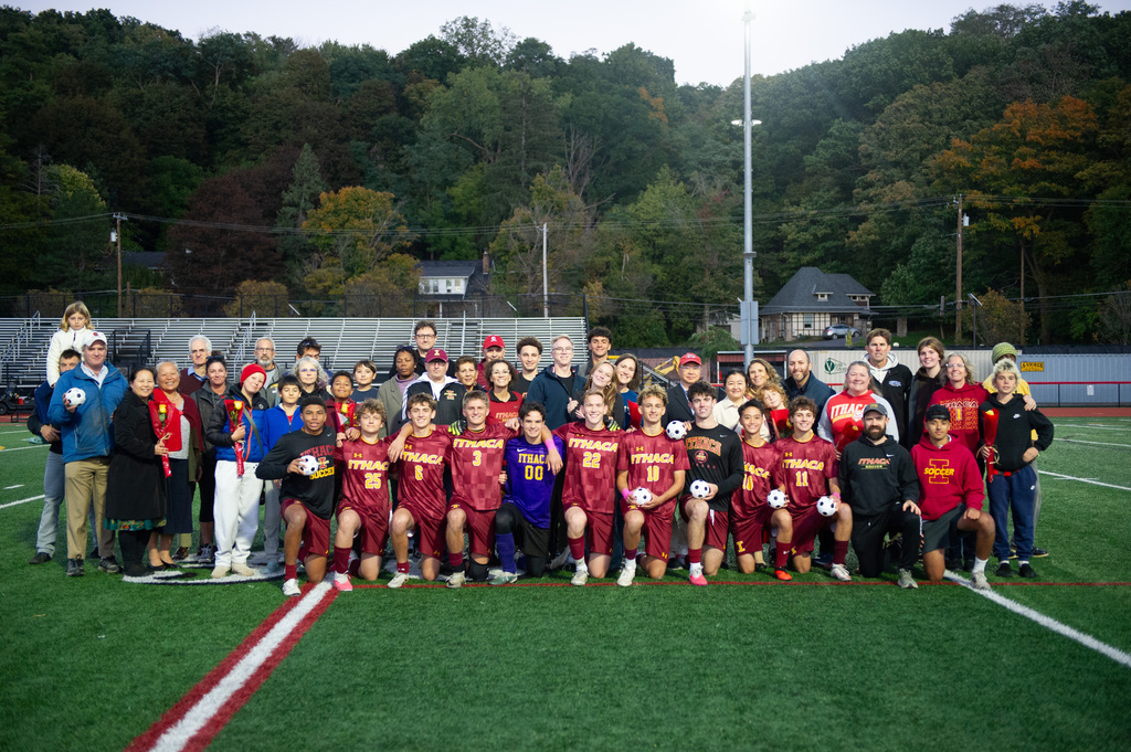 A group of people on a soccer field wearing red uniforms. They are posing for a photo.