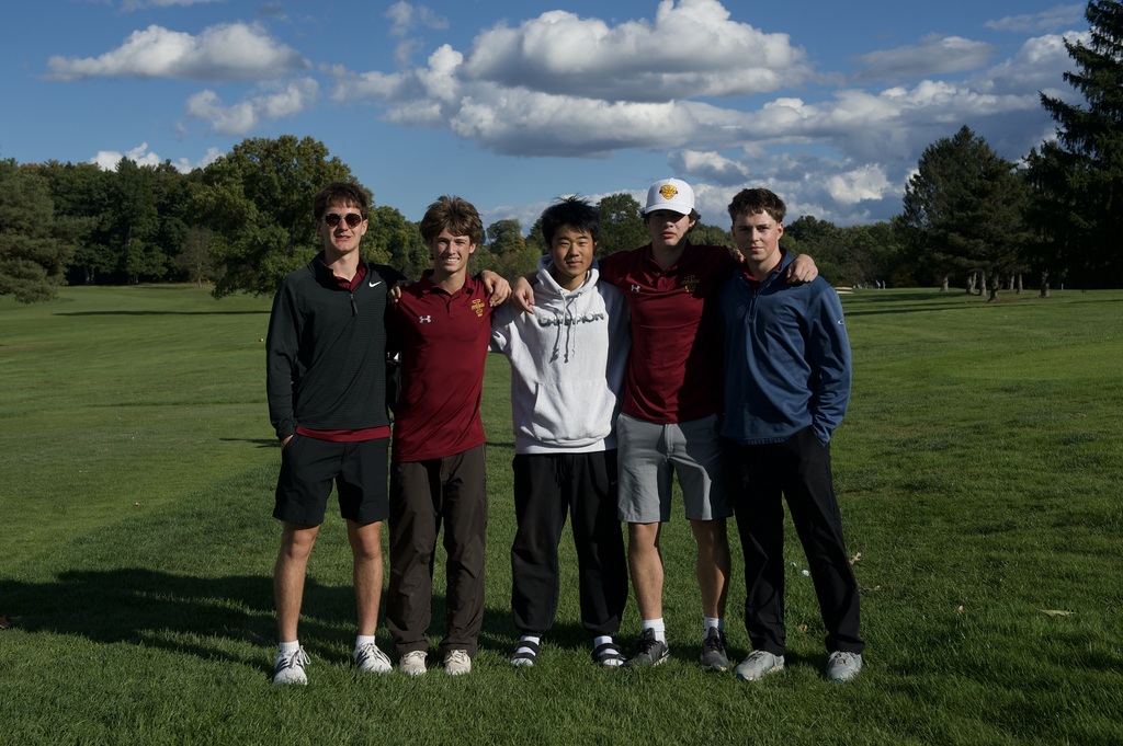 Five boys on the golf team pose for a photo on the golf course